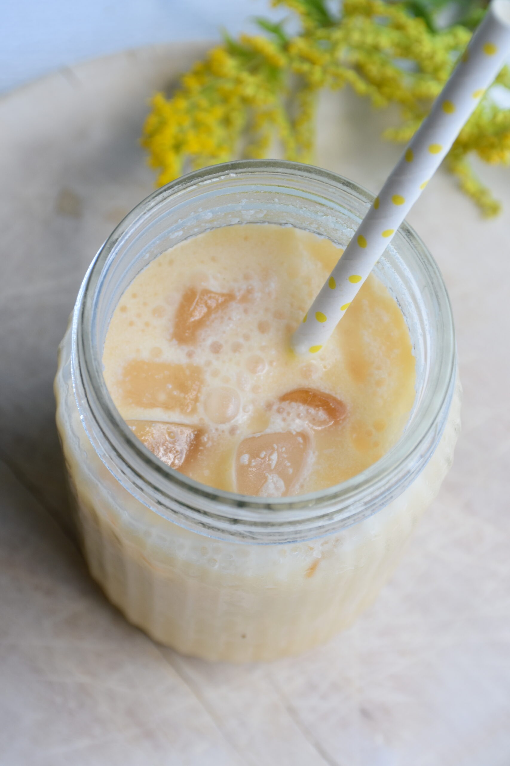 Sanddorn-Kokos-Lassi im Glas mit Strohhalm und Eiswürfel, fructosearm und vegan
