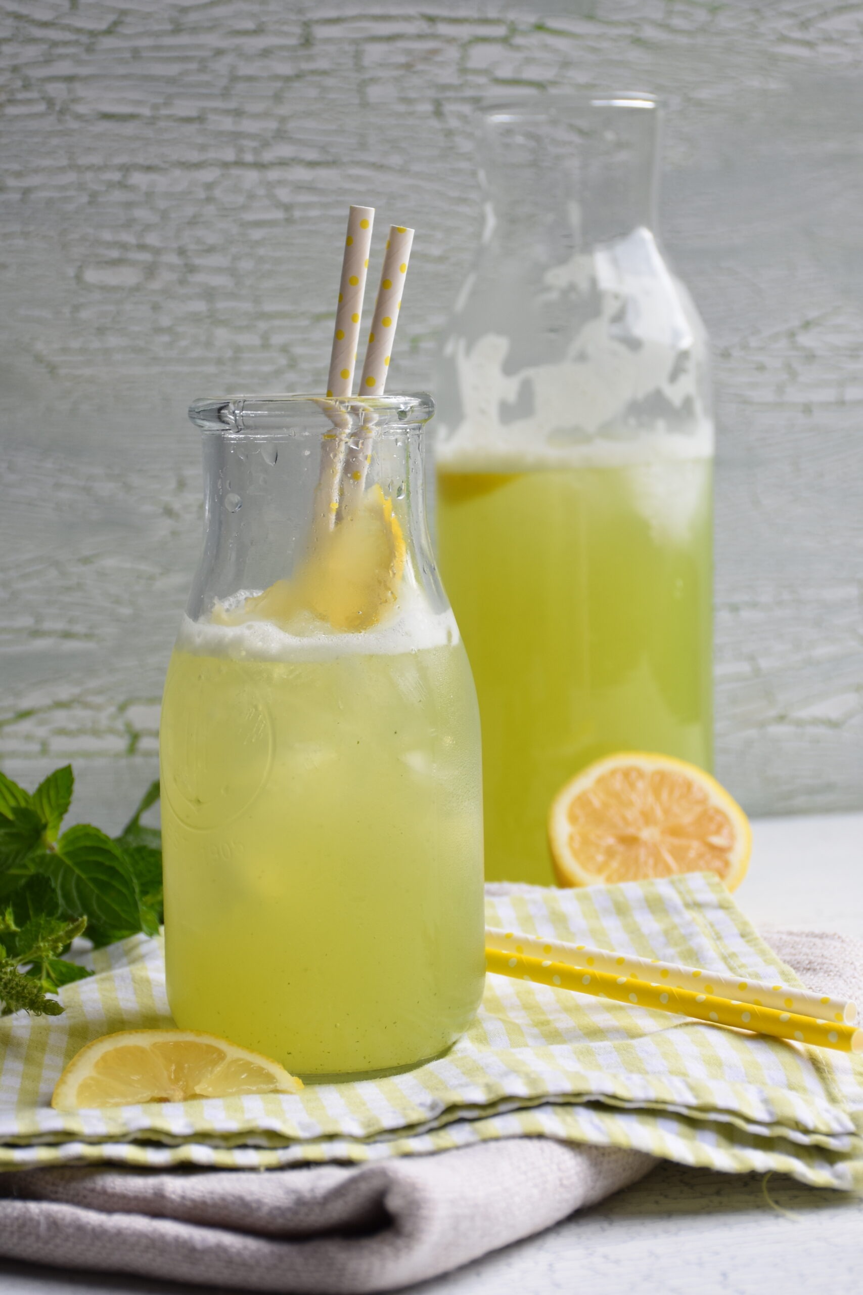 Zitronen-Limonade mit Pfefferminze in einem Glas und Krug, mit Zitronen garniert, ohne Zucker, mit Stevia gesüßt.